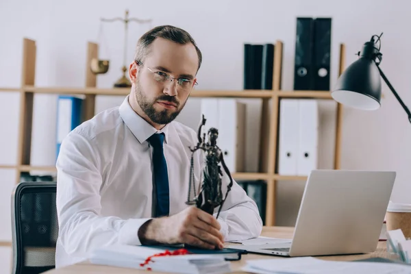 Selective focus of lawyer in eyeglasses with femida at workplace in office — Stock Photo