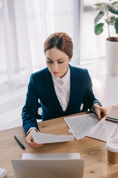 Hochwinkelaufnahme einer konzentrierten Geschäftsfrau mit Papieren am Arbeitsplatz mit Laptop im Büro — Stockfoto