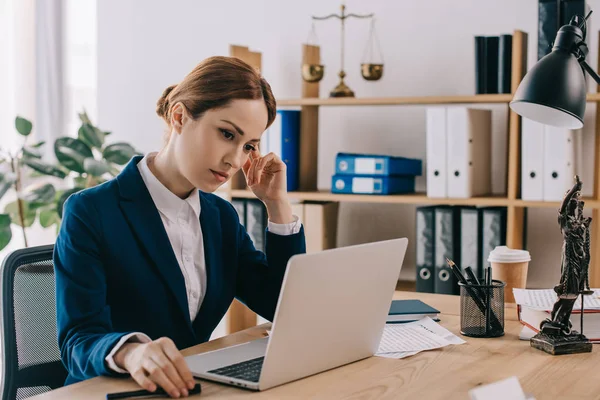 Female lawyer in suit working on laptop at workplace in office — Stock Photo