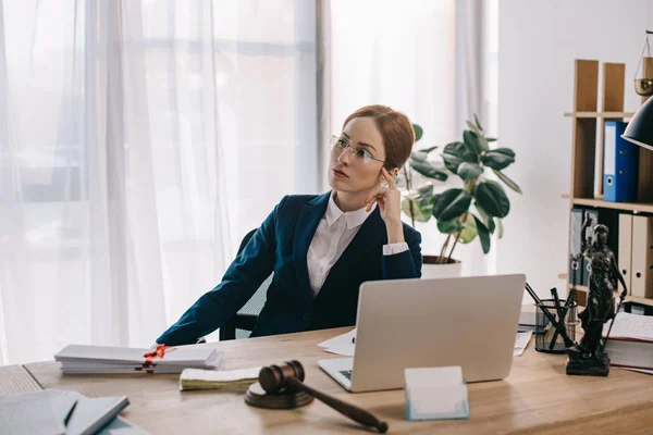 Retrato de advogada feminina pensativa no local de trabalho com martelo e laptop no escritório — Fotografia de Stock