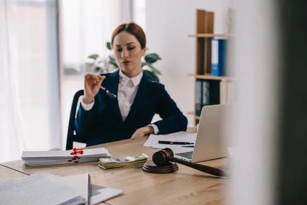 Anwältin am Arbeitsplatz mit Hammer, Dollarnoten, Bestechungsgeld und Laptop im Büro — Stockfoto