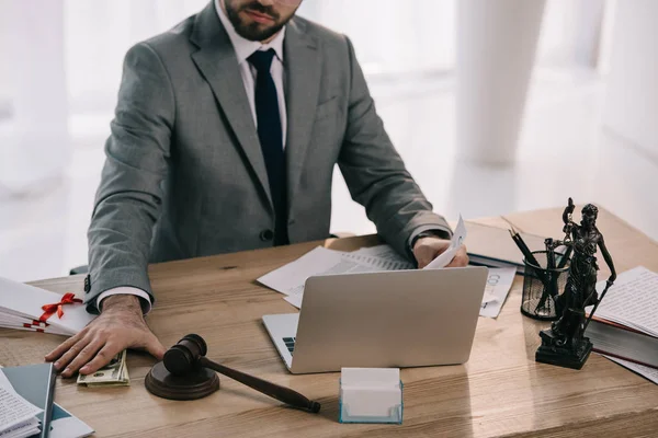 Обрізаний знімок адвоката, який бере хабар на робочому місці з паперами та ноутбуком в офісі — стокове фото