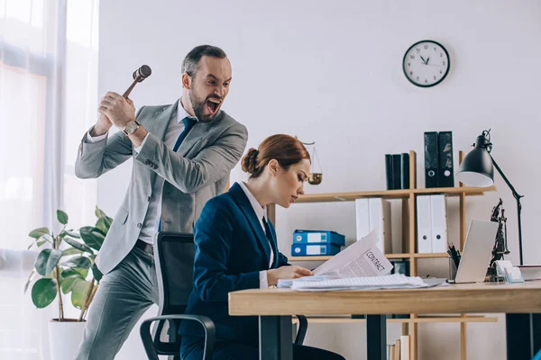 Angry lawyer pretending to hit colleague with gavel in hands in office — Stock Photo