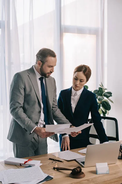 Abogados en trajes que trabajan juntos en el proyecto en el lugar de trabajo con mazo y portátil en la oficina - foto de stock