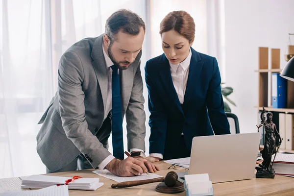 Avocats en costumes travaillant ensemble sur le projet sur le lieu de travail avec marteau et ordinateur portable dans le bureau — Photo de stock