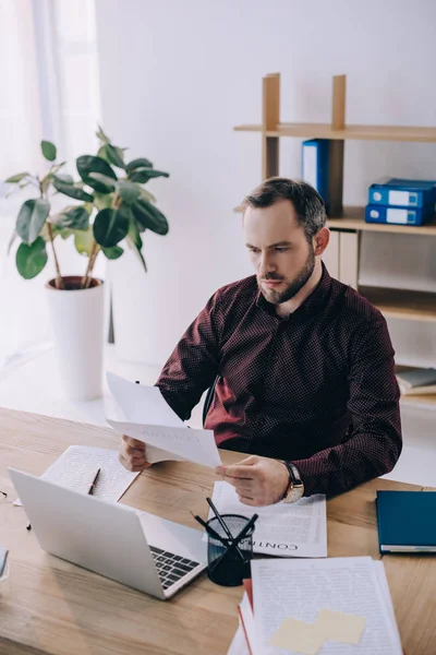 Ritratto di uomo d'affari che fa scartoffie sul posto di lavoro con laptop in ufficio — Foto stock