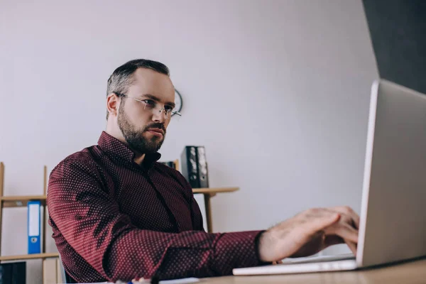 Homme d'affaires concentré travaillant sur ordinateur portable au travail dans le bureau — Photo de stock