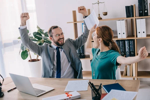 Happy lawyer and client at workplace with documents and laptop in office — Stock Photo