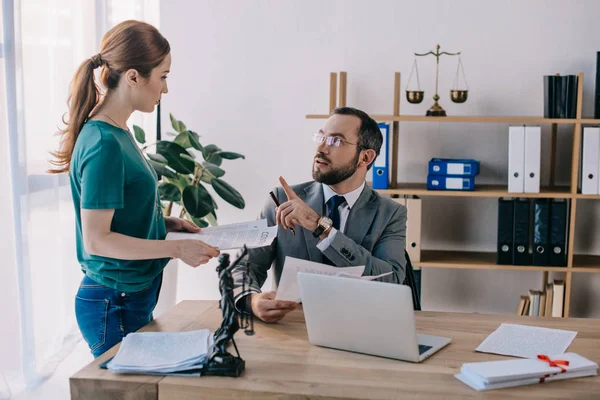Avocat en lunettes et client discutant du contrat sur le lieu de travail avec ordinateur portable au bureau — Photo de stock