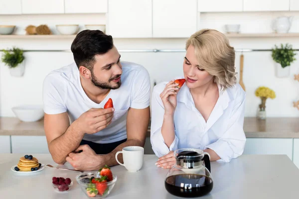 Feliz jovem casal comendo morangos de manhã — Fotografia de Stock