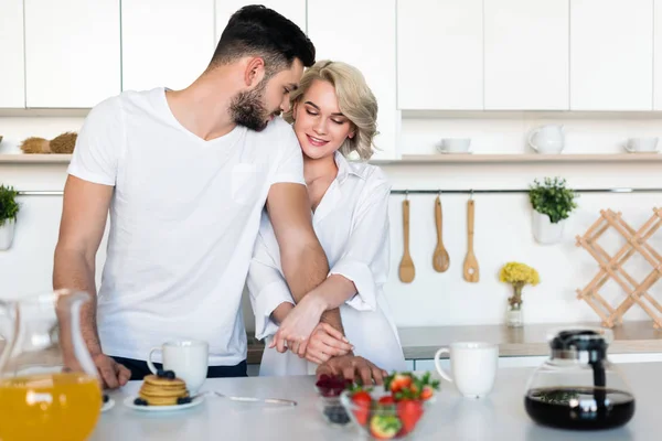 Beau jeune couple câlin tout en prenant le petit déjeuner ensemble — Photo de stock