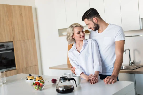 Glückliches junges Paar lächelt sich beim gemeinsamen Frühstück an — Stockfoto