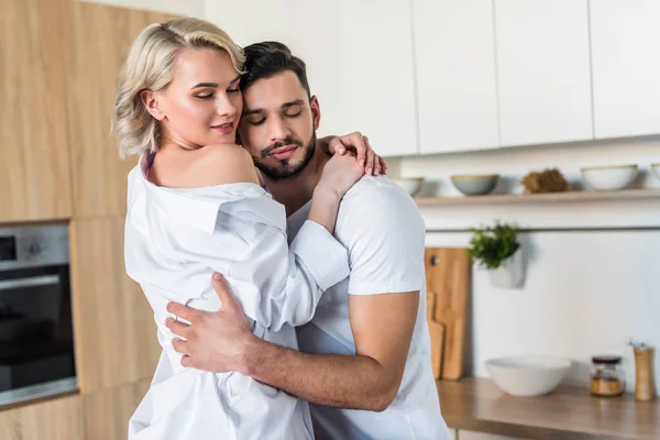 Feliz sensual joven pareja abrazándose en cocina - foto de stock