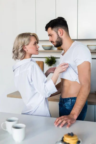 Seitenansicht des verführerischen jungen Paares, das sich morgens in der Küche anschaut — Stockfoto