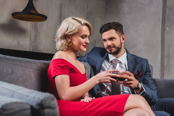 Hermosa pareja de moda en traje y vestido rojo beber vino juntos - foto de stock