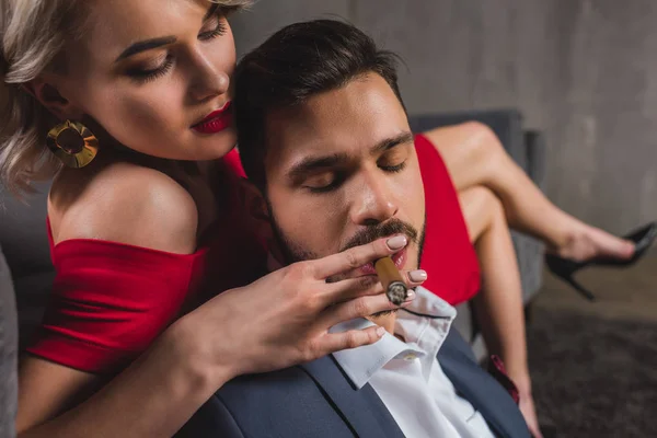 Close-up view of sexy girl in red dress holding cigar while boyfriend smoking it — Stock Photo
