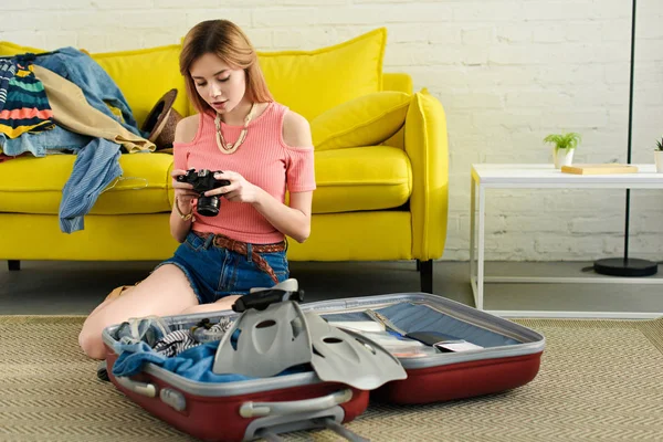 Mädchen schaut in Kamera, während sie Koffer für den Urlaub packt — Stockfoto