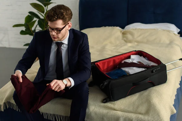 Красивый бизнесмен в костюме упаковывает багаж для деловой поездки — стоковое фото