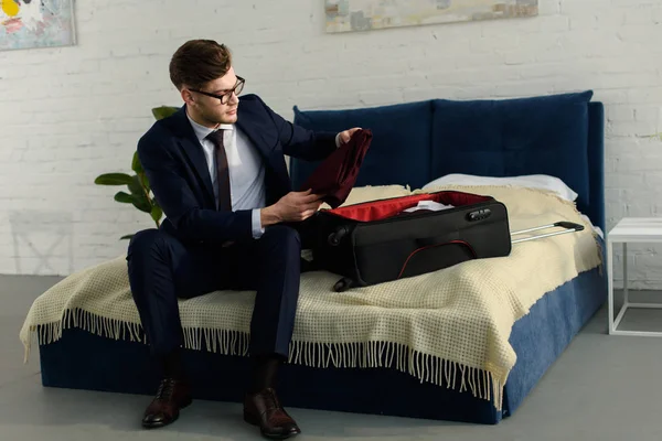 Handsome businessman in suit packing bag for business trip — Stock Photo