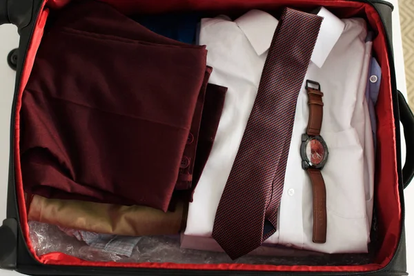 Верхний вид чемодана с костюмом, галстук и часы для деловой поездки — стоковое фото