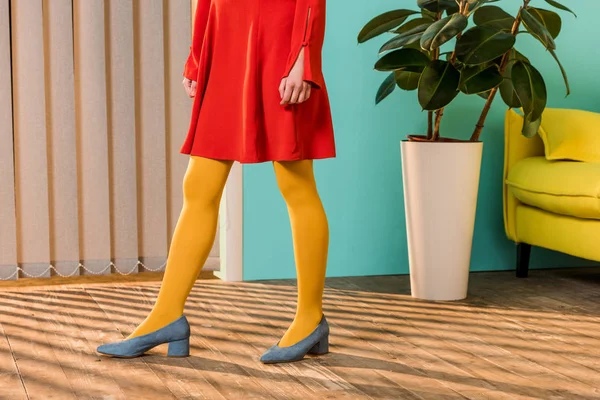 Recortado tiro de mujer en ropa brillante de pie en habitación colorida, concepto de casa de muñecas - foto de stock