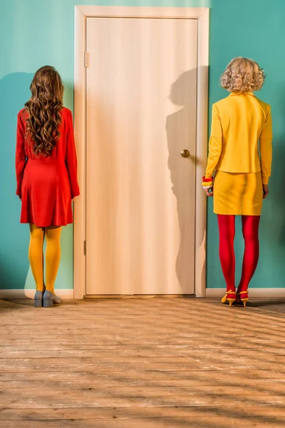 Вид ззаду жінки в стилі ретро, що стоїть біля дверей в барвистій квартирі, концепція лялькового будинку — стокове фото