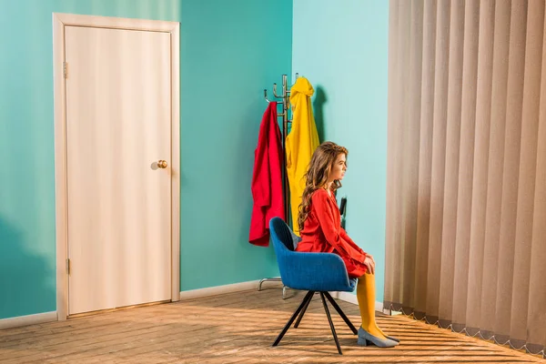 Вид збоку стомлена ретро-стилізована жінка сидить на стільці в світлій квартирі, концепція лялькового будинку — стокове фото