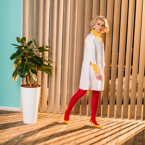 Красивый врач в стиле ретро в красочном платье и белом халате прогулка в клинике — стоковое фото