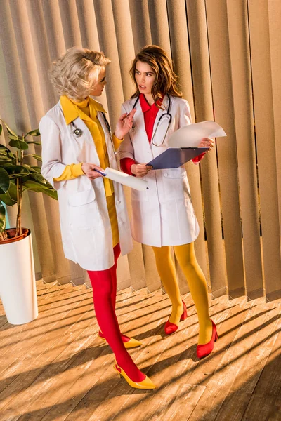Schöne Ärzte im Retro-Stil mit Klemmbrettern im Gespräch in der Klinik — Stockfoto