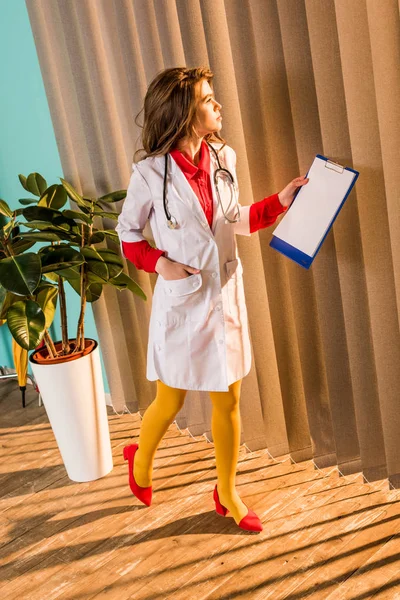 Beautiful retro styled doctor walking with clipboard in clinic — Stock Photo