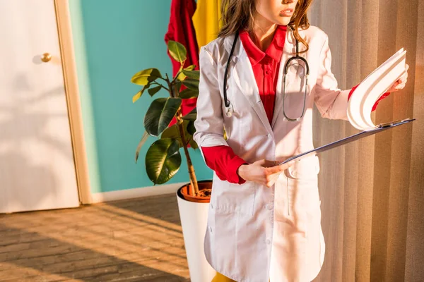 Abgeschnittenes Bild eines im Retro-Stil gestylten Arztes mit Blick auf das Klemmbrett in der Klinik — Stockfoto