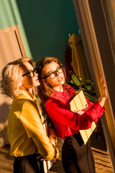 Привабливі ретро стилі бізнес-леді в барвистих блузках з папками, дивлячись на вікно в офісі — стокове фото
