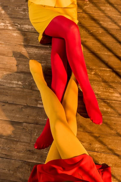 Cropped image of girls in colored tights and dresses sitting on floor at home — Stock Photo