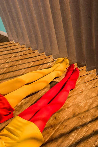 Cropped image of girls in red and yellow tights and dresses sitting on floor at home — Stock Photo