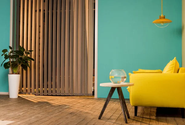 Жовтий диван і акваріум з рибою на столі у вітальні — стокове фото