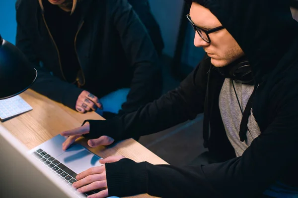 Serious hacker working on new malware with accomplice  in dark room — Stock Photo