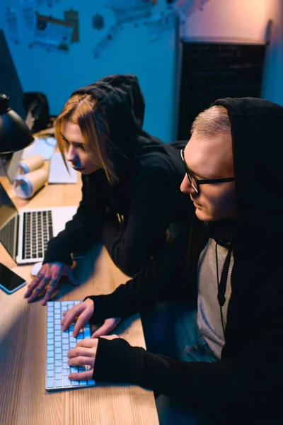 Pareja de hackers seguros de sí mismos trabajando en malware juntos en la habitación oscura - foto de stock