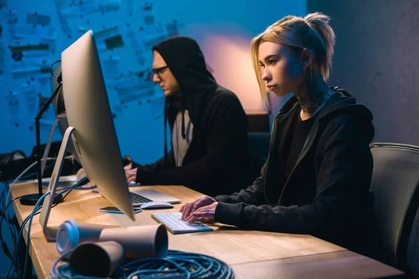 Confident couple of hackers working on malware in dark room — Stock Photo