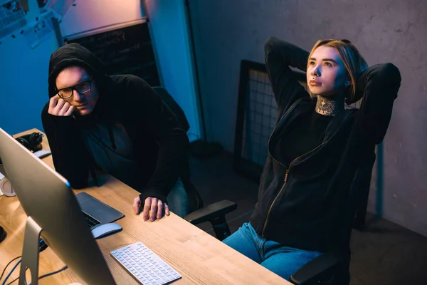 Couple of thoughtful young hackers at workplace — Stock Photo