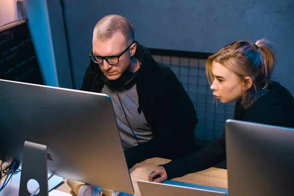 Junges Hackerpaar schaut gemeinsam am Arbeitsplatz auf Computerbildschirm — Stockfoto