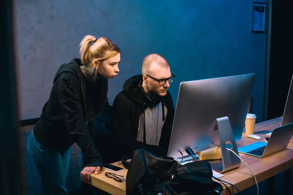 Молодая пара хакеров смотрит на экран компьютера вместе — стоковое фото