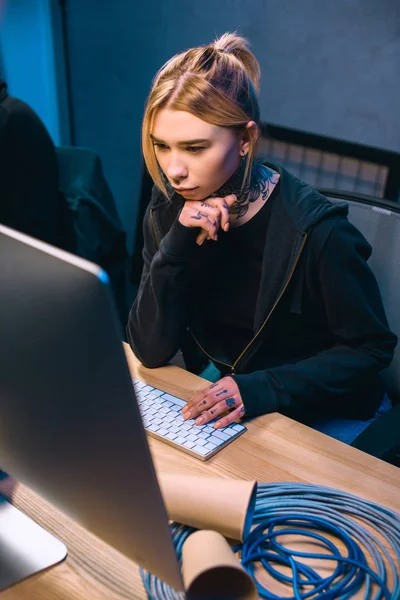 Junge nachdenkliche Hackerin blickt auf Computerbildschirm — Stockfoto