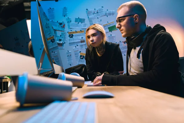 Thoughtful couple of hackers working with computer together in dark room — Stock Photo