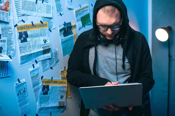 Young hacker developing malware with laptop in dark room — Stock Photo