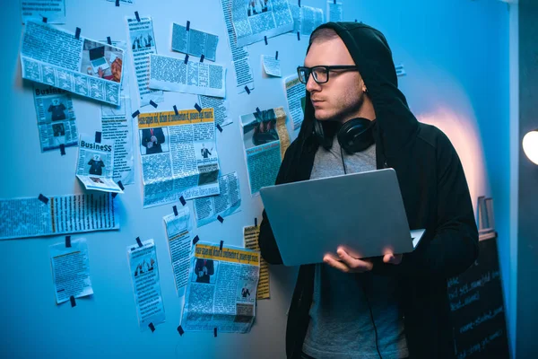 Young serious hacker developing malware with laptop in dark room — Stock Photo