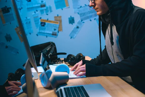 Cropped shot of hooded young hacker working with computer — Stock Photo