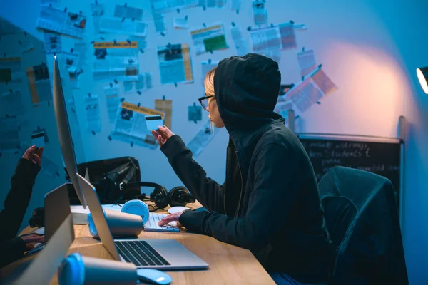 Female hacker with stolen credit card working with computer — Stock Photo