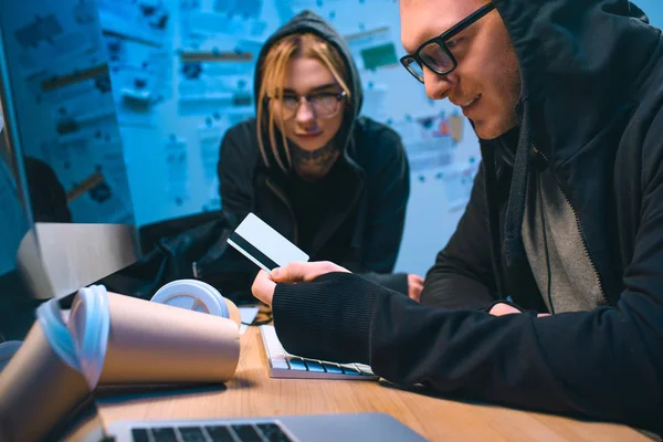 Excited couple of hackers with stolen credit card at workplace — Stock Photo