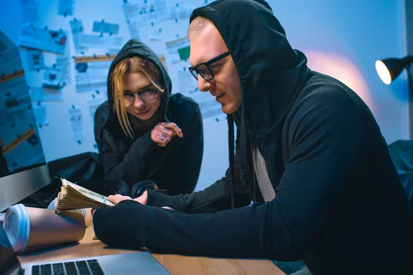 Aufgeregtes Hackerpaar mit Stapel Bargeld am Arbeitsplatz — Stockfoto