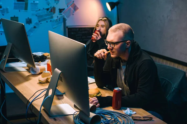 Hackers bebiendo cerveza y comiendo comida chatarra mientras trabajan en malware - foto de stock